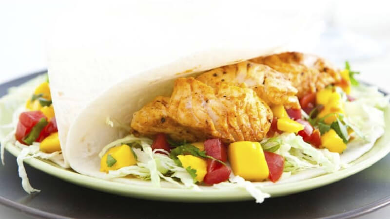 Un taco moelleux avec de la salsa de poisson et de mangue sur une assiette
